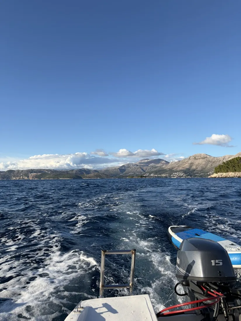 An outboard motor and foaming wake, with a paddleboard trailing behind the boat