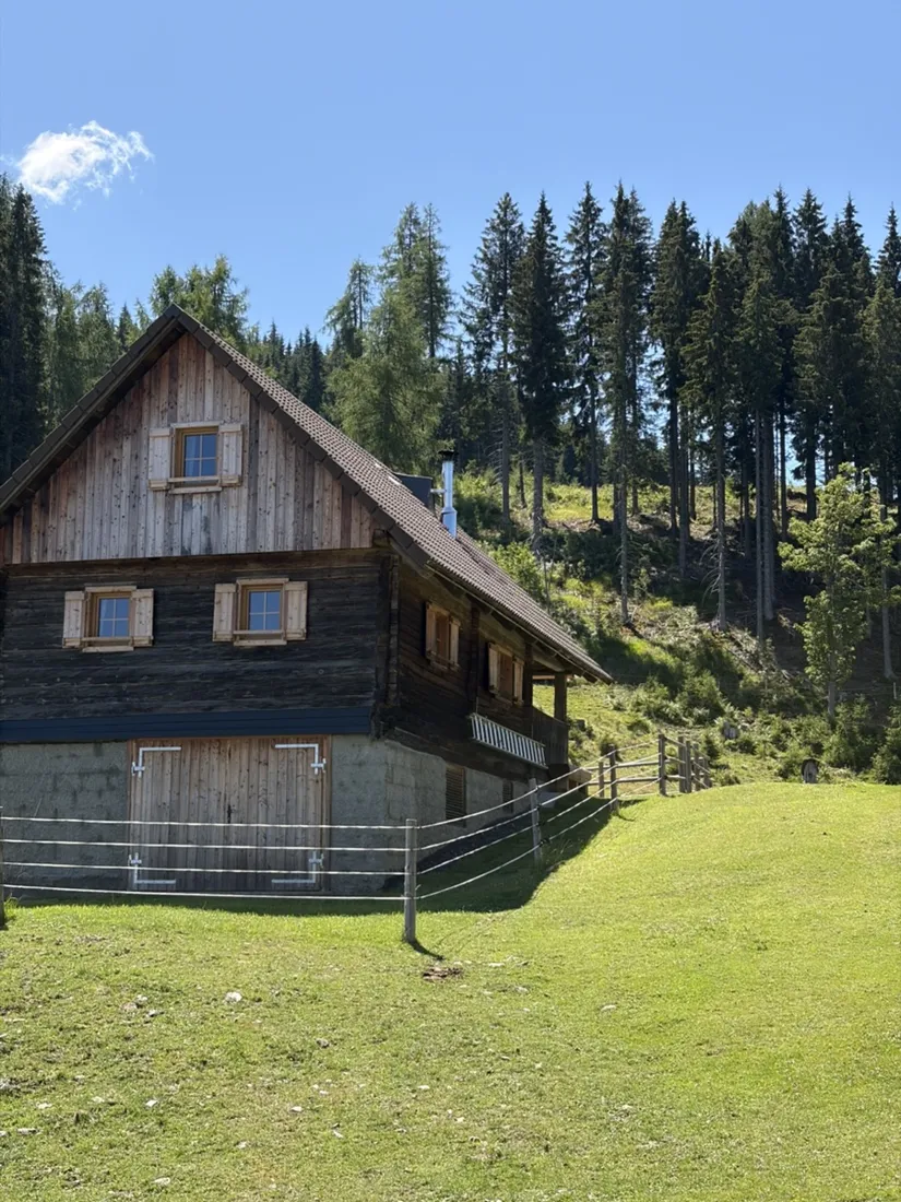 Eine traditionelle, schindelgedeckte Almhütte auf der hohen Sommerweide