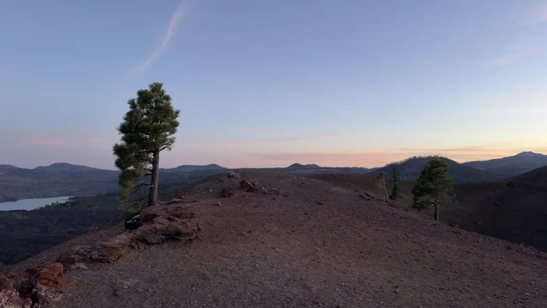 The Cinder Cone silhouetted against dusk light with a solitary pine