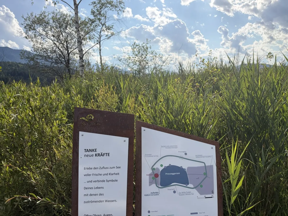 A “Slow Trail” station in the reeds, its panel mapping the loop from the Strandbad Hermagor around the lake