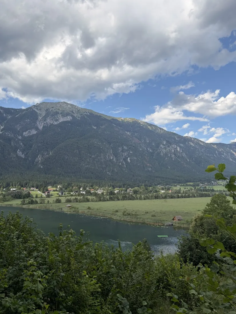 The still, drinking-water-clear water of the Pressegger See seen through the trees from the trail