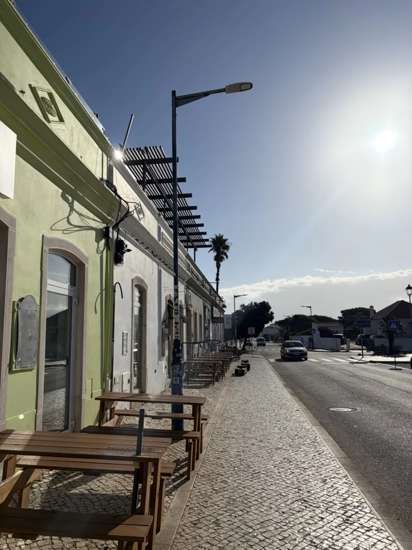 Eine ruhige Seitenstraße in Sagres kurz nach acht Uhr morgens, die Cafébänke noch gestapelt, die Sonne tief über den Dächern