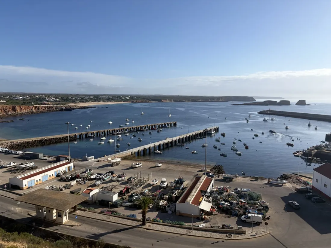 Der Porto da Baleeira von oben: die Fischerflotte an den Stegen, Gerät auf der Kaimauer, dahinter die Felseninseln vor Martinhal