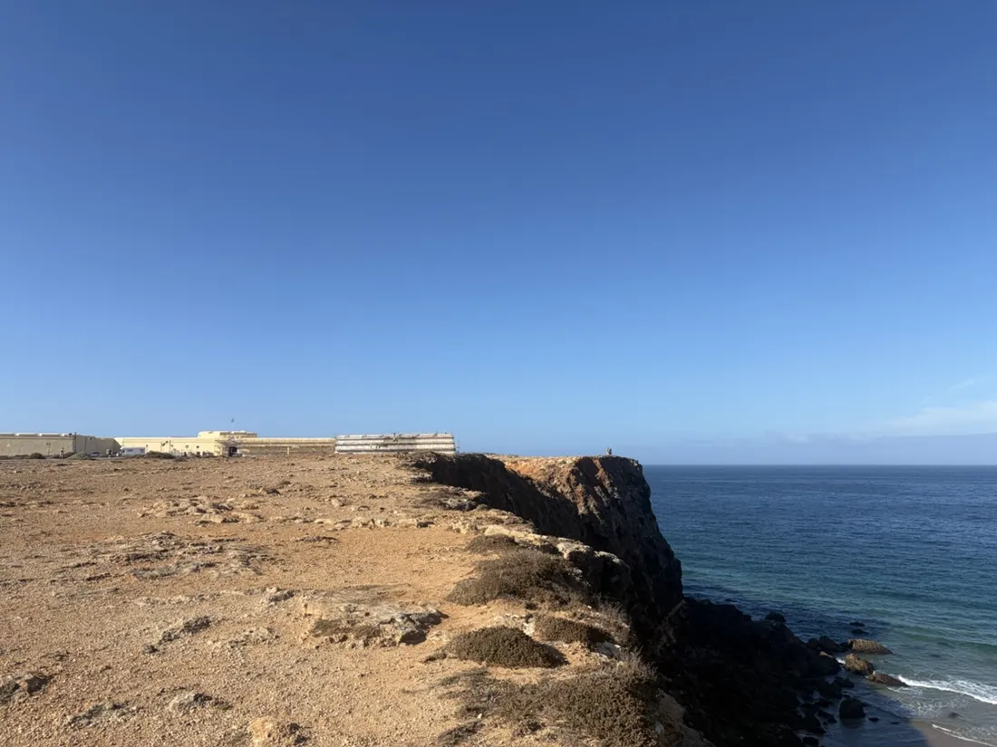 Das blanke Kalkplateau über dem Tonel endet in einer niedrigen Abbruchkante, am Horizont die lange Mauer der Festung von Sagres