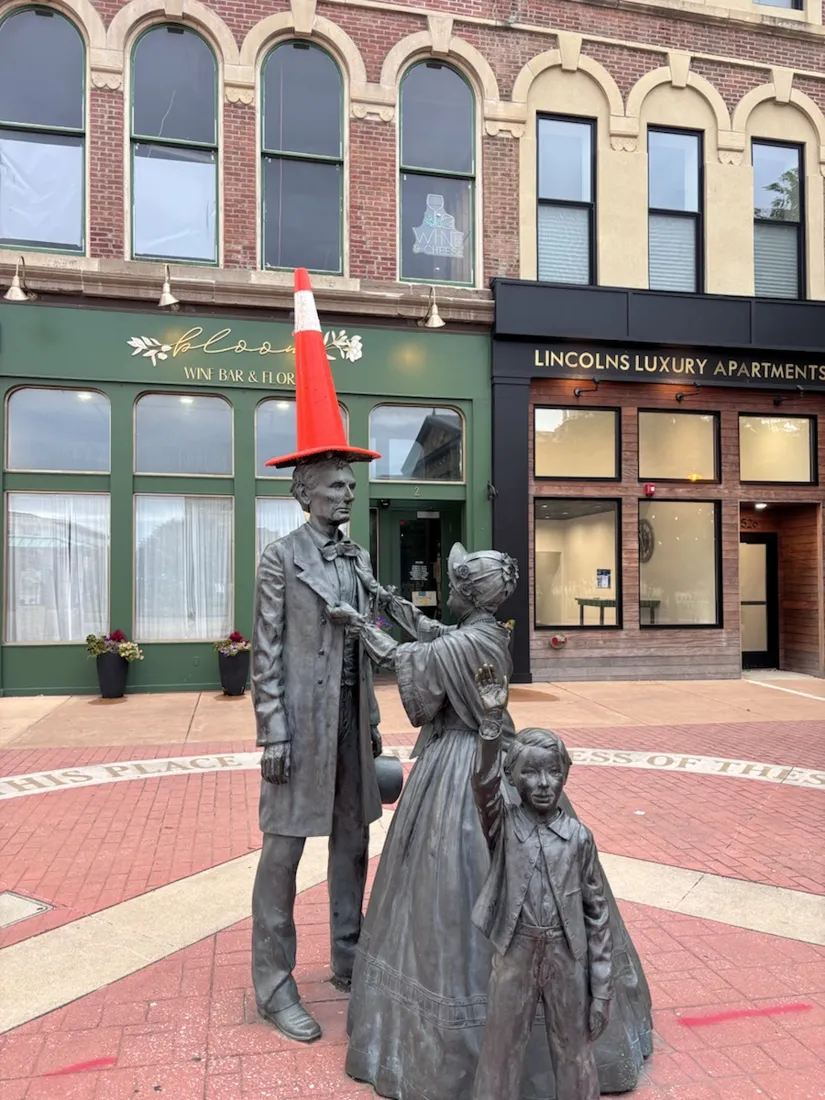 The bronze Lincoln family statue downtown — a traffic cone perched on Lincoln's hat